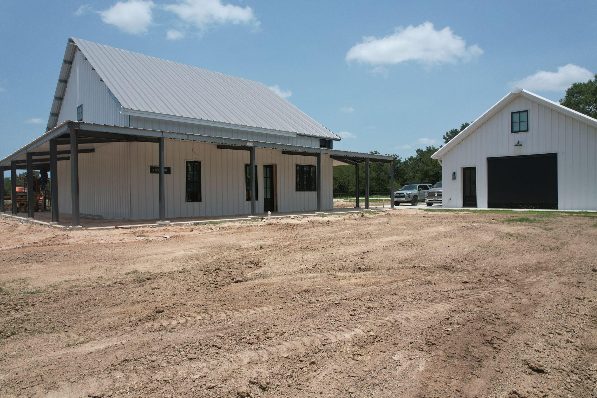 White residential metal building with covered porch and detached garage by Muleshoe Buildings in the Brazos Valley, TX